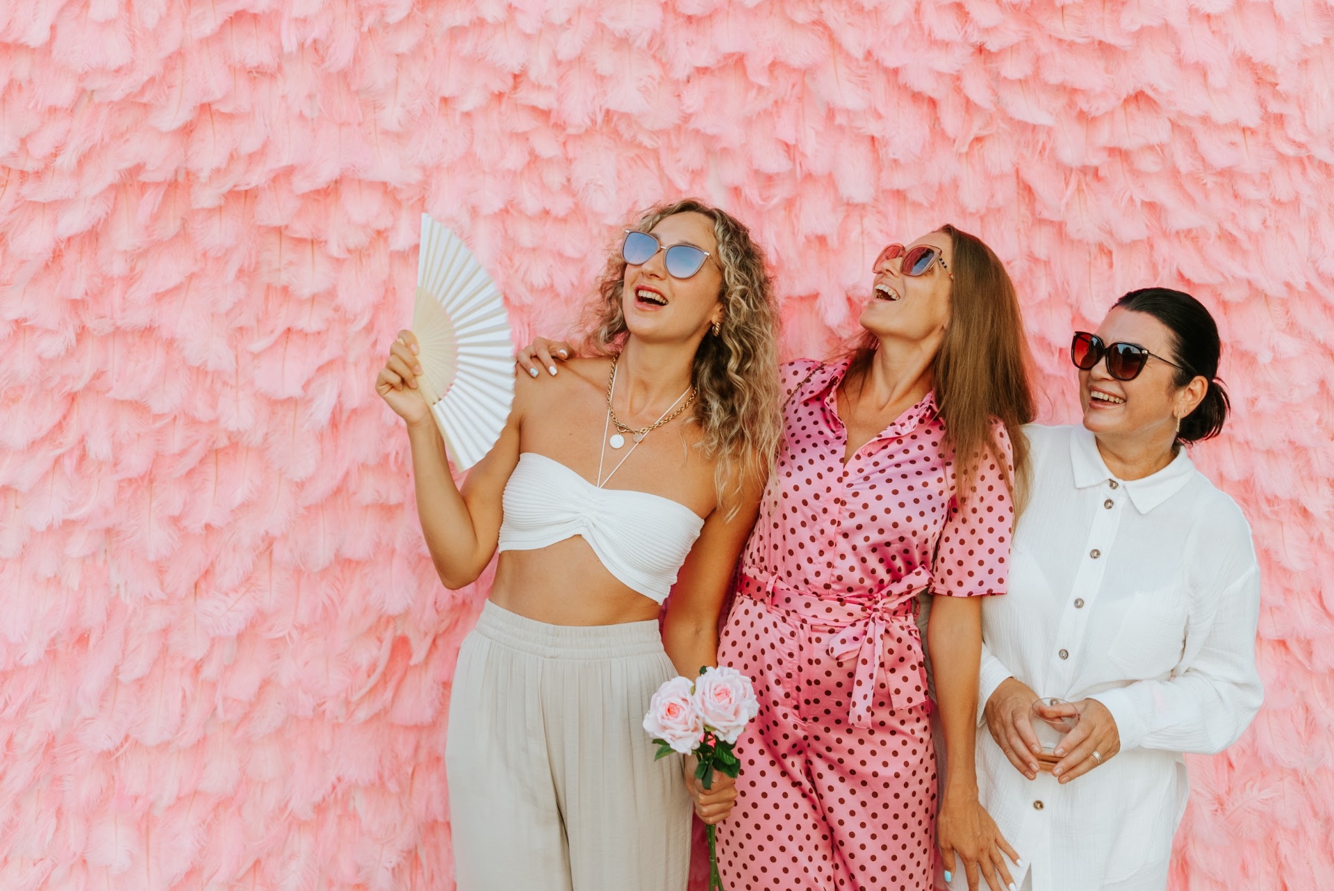 Rosé Days guests laughing against a pink feather wall